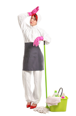 Tired housewife in protective suit and with cleaning supplies on white backgroundの写真素材