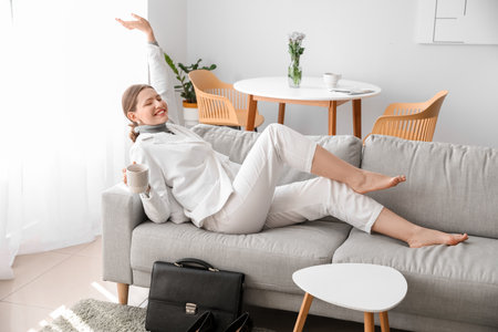 Businesswoman relaxing on sofa after work at homeの写真素材