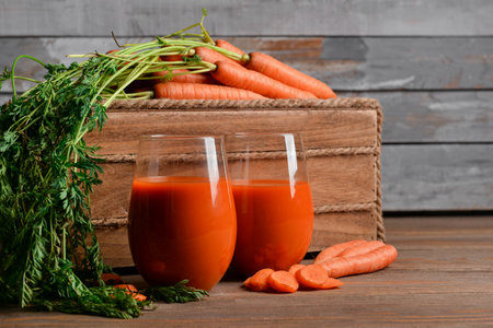 Two glasses of fresh carrot juice on wooden tableの写真素材