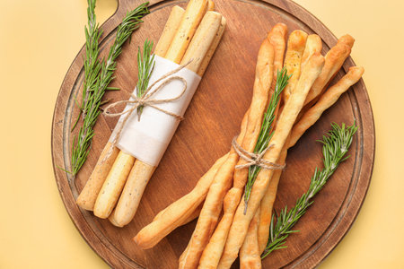 Wooden board with bunches of tasty Italian Grissini on yellow backgroundの写真素材