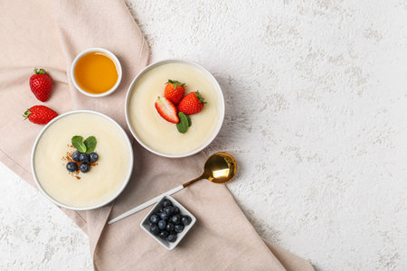 Bowls of tasty semolina porridge with strawberry and blueberry on light grunge backgroundの写真素材