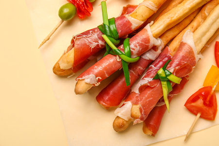 Tasty Italian Grissini with bacon on yellow background, closeupの写真素材