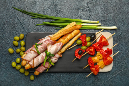 Board of tasty Italian Grissini with bacon on dark backgroundの写真素材
