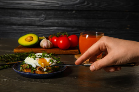 Woman cutting tasty egg Benedict at tableの写真素材