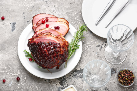 Plate with tasty smoked ham and wine glasses on gray grunge backgroundの写真素材