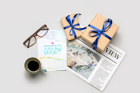 Composition with greeting card, newspaper, eyeglasses, cup of coffee and gifts for Father's Day celebration on white backgroundの写真素材