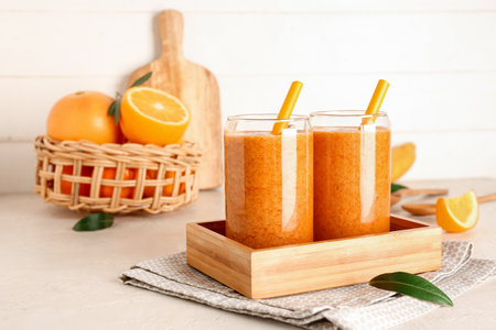 Glasses of healthy orange smoothie on light backgroundの写真素材