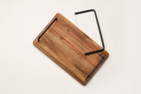 Wooden kitchen board with cheese slicer on light backgroundの写真素材