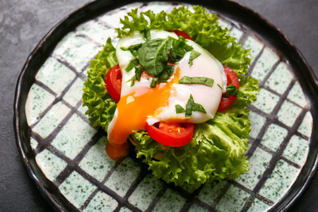 Plate with tasty eggs Benedict on black grunge table, closeupの写真素材