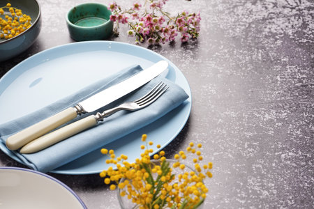 Clean plate with cutlery and flowers on gray grunge table