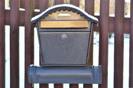View of metal mailbox with snow on wooden fence, closeupの写真素材