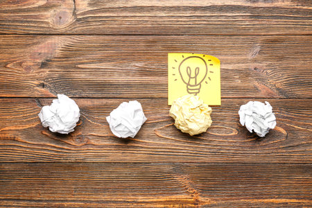 Crumpled paper with drawn light bulb on wooden background. insight concept