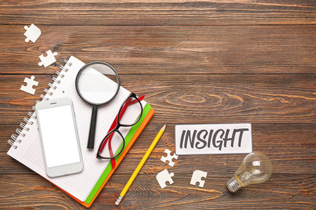 Word INSIGHT, puzzle pieces, notebook, mobile phone and magnifier on wooden backgroundの写真素材
