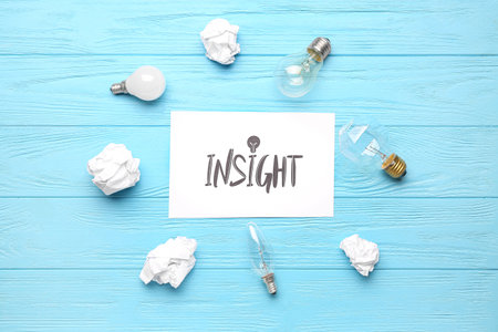 Word INSIGHT with crumpled paper and light bulbs on blue wooden backgroundの写真素材