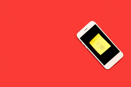 Sticky paper with drawn light bulb and mobile phone on red background. insight conceptの写真素材