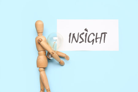 Paper with word INSIGHT, wooden mannequin and light bulb on blue backgroundの写真素材