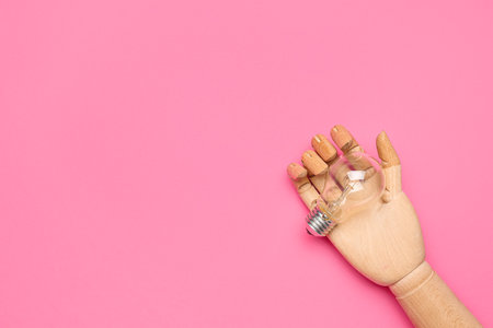 Wooden hand with light bulb on pink background. insight conceptの写真素材
