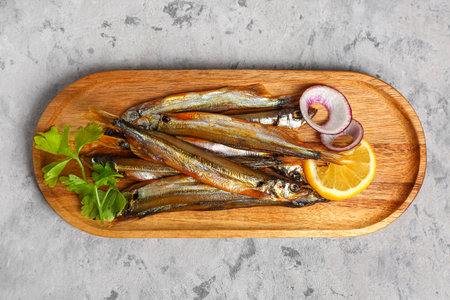 Board with delicious smoked capelin on gray grunge backgroundの写真素材