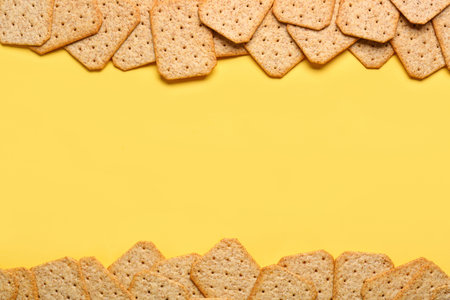 Frame made of tasty crackers on yellow background