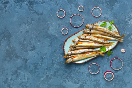 Plate with delicious smoked capelin on blue grunge backgroundの写真素材