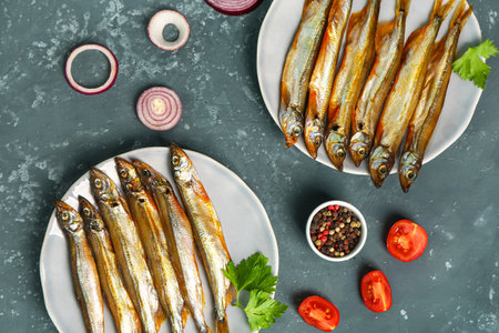 Plates with delicious smoked capelin on gray grunge backgroundの写真素材