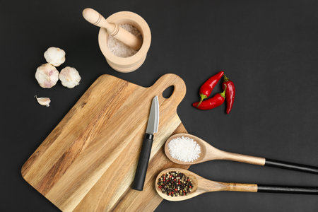Wooden cutting board and spices on dark backgroundの写真素材