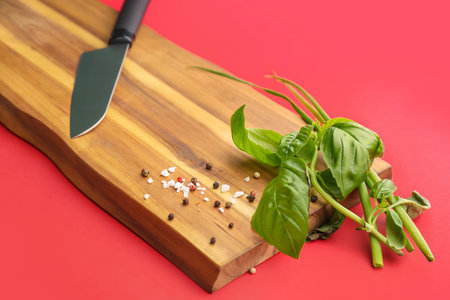Wooden board with herbs, spices and knife on red background, closeupの写真素材