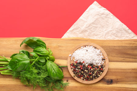 Wooden board with fresh herbs and spices on red background, closeupの写真素材