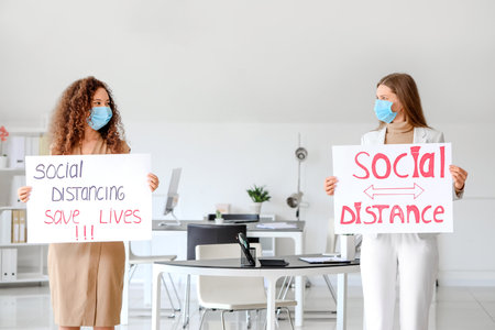 Colleagues with text SOCIAL DISTANCE. SAVE LIVES on papers in office. concept of epidemicの写真素材