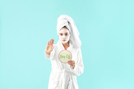 Woman after shower with text DAY OFF on paper sheet showing stop gesture against color backgroundの写真素材
