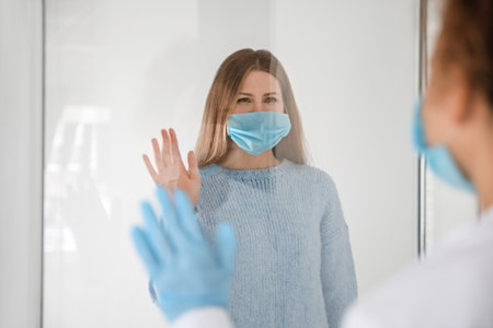 Female doctor and patient in protective masks greeting each other in clinic. concept of coronavirus epidemicの写真素材