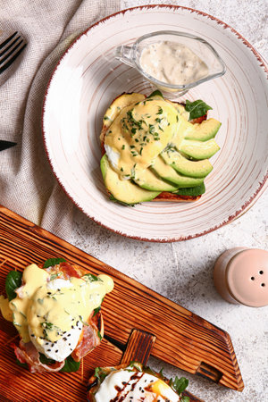 Board and plate with delicious eggs Benedict on white tableのeditorial素材
