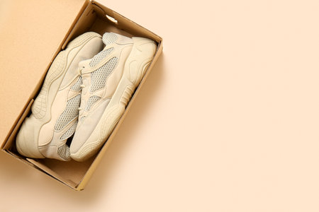 Cardboard box with sports shoes on beige backgroundの写真素材