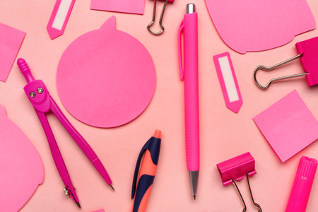 Composition with pens, sticky notes and paperclips on pink backgroundの写真素材