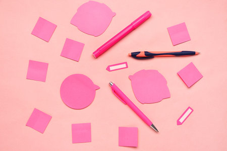 Composition with pens, sticky notes and paperclips on pink background