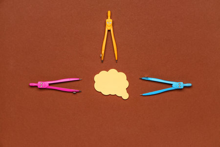Composition with color drawing compasses and sticky note on brown background