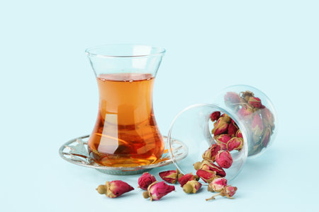 Glass of Turkish tea and dry roses on light blue backgroundの写真素材