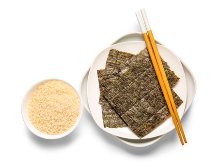 Plates with natural nori sheets, chopsticks and bowl of rice isolated on white backgroundの写真素材