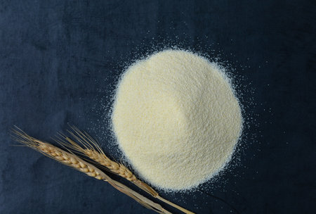 Heap of raw semolina and spikelets on blue backgroundの写真素材