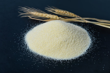 Heap of raw semolina and spikelets on blue backgroundの写真素材