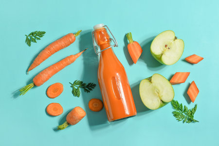 Glass bottle of tasty carrot juice on blue backgroundの写真素材