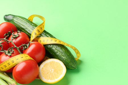 Vegetables, lemon and yellow measuring tape on green background. Diet conceptの写真素材