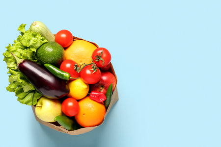 Paper bag with vegetables and fruits on light blue backgroundの写真素材