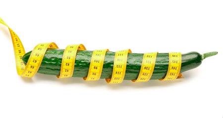 Cucumber and yellow measuring tape on white background. Diet conceptの写真素材