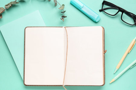 Composition with blank notebook, glasses and pens on turquoise backgroundの写真素材