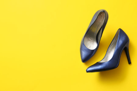 Pair of stylish high heeled shoes on yellow backgroundの写真素材