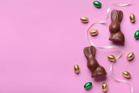 Chocolate bunnies, Easter eggs and ribbon on pink backgroundの写真素材