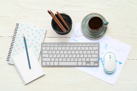 Composition with keyboard, coffee and blank notepad on light wooden backgroundの写真素材