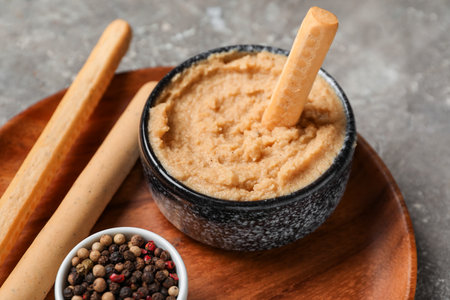 Bowl of tasty hummus with Italian Grissini on table, closeupの写真素材
