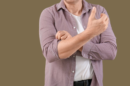 Mature man rolling up his sleeve on green background, closeupの写真素材